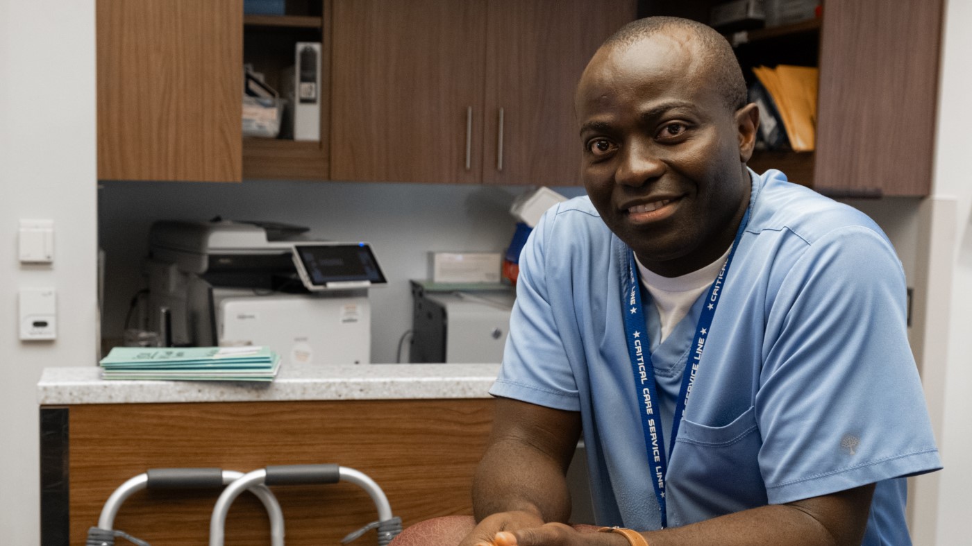 A Black man in scrubs in a VA exam room.