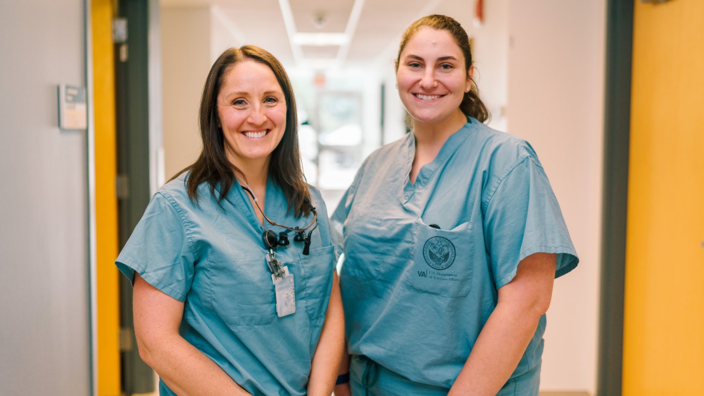 Two smiling VA healthcare workers in a hallway in a VA facility.