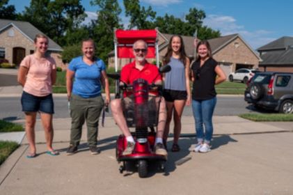 Vietnam Veteran Mike Donnelly poses with engineering students from the University of Cincinnati who designed and built a convertible scooter cover to protect Mike from the elements while using his electric scooter that was provided to him by the Veterans Affairs Hospital in Cincinnati.