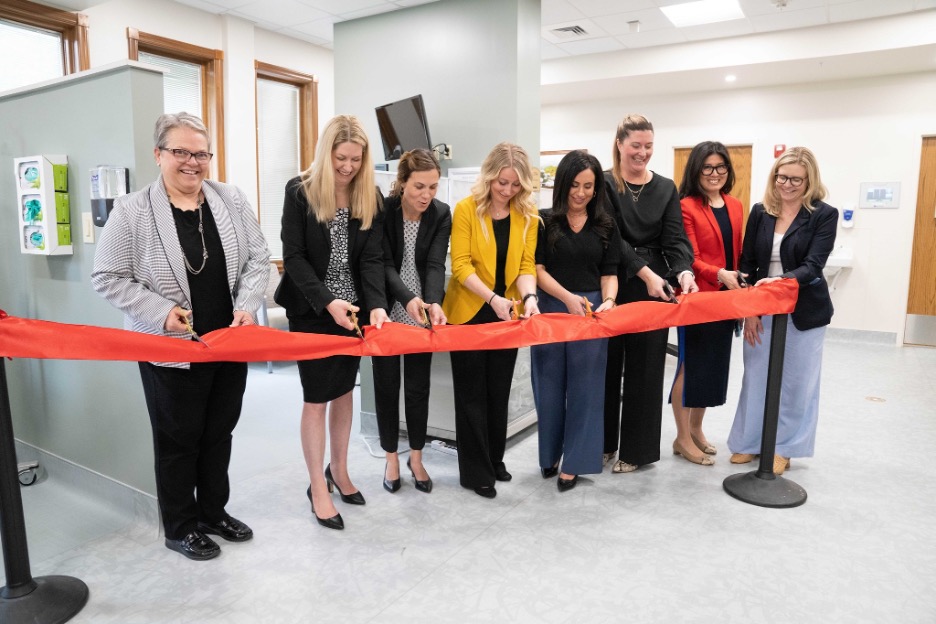 A group of providers cut a large red ribbon for a Close to Me oncology clinic.