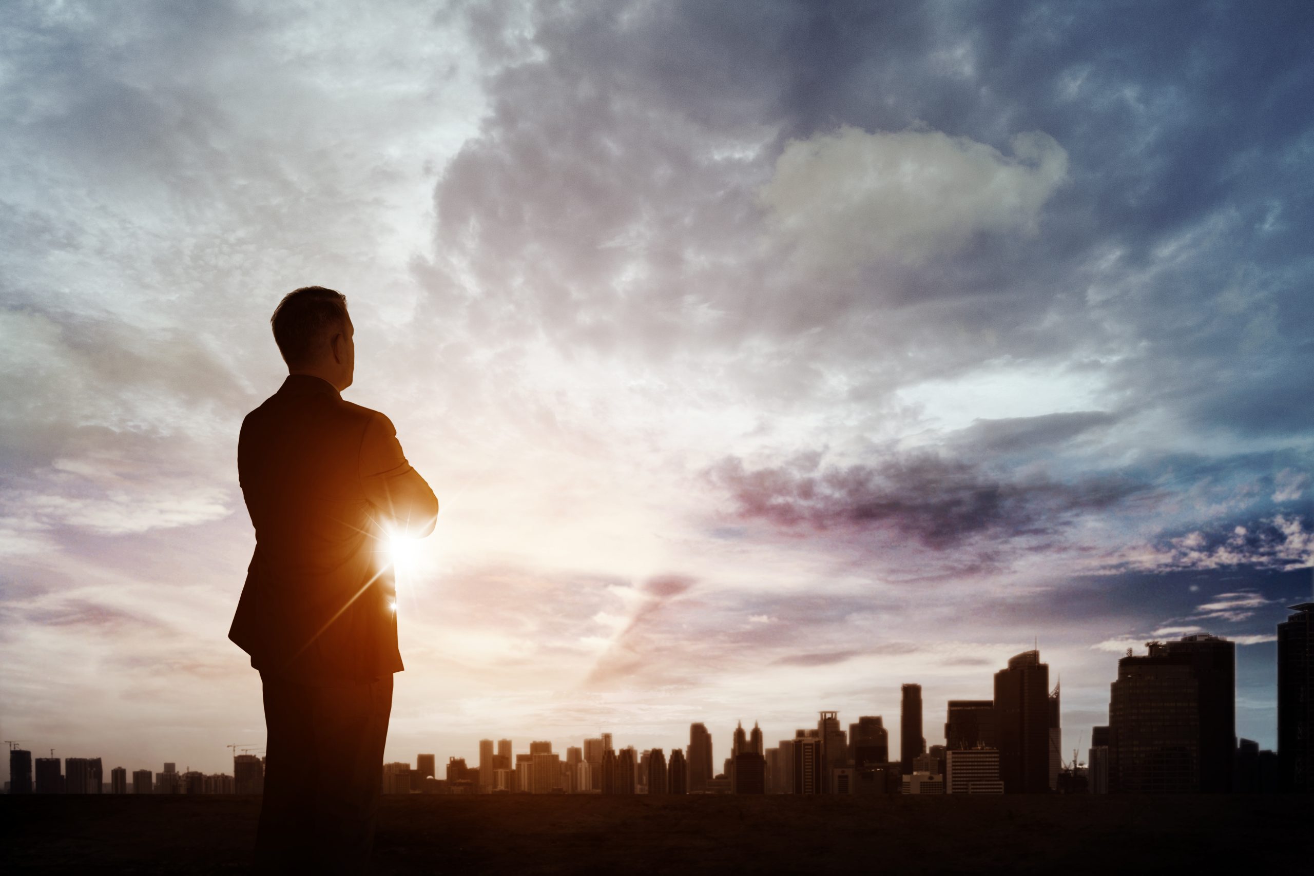 Man in business suit looking out at city skyline. Career inspiration.