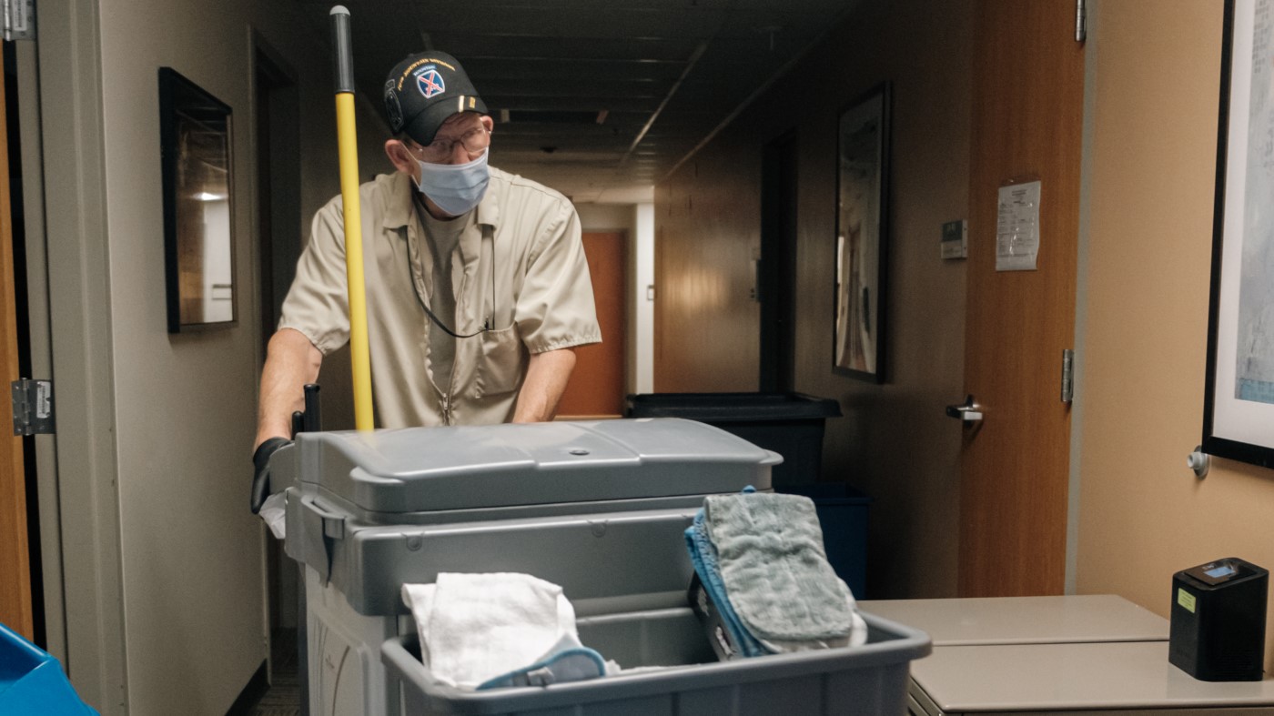 An environmental services technician takes his cleaning cart through the halls of a VA facility.