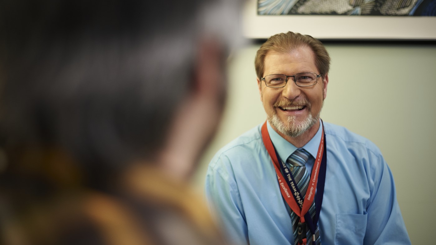 A VA psychiatrist smiles in conversation with a Veteran patient.