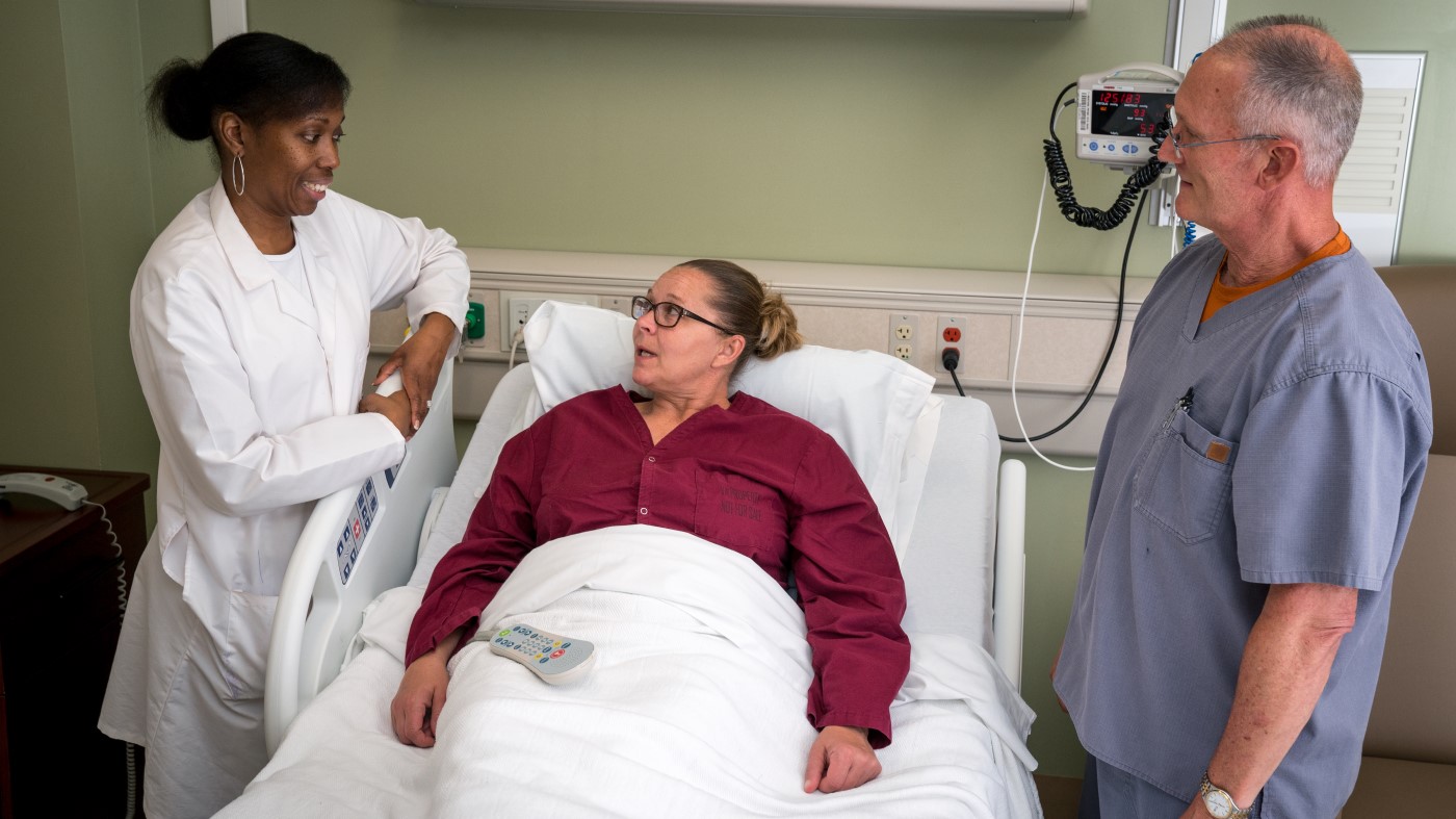 Two clinical providers discuss treatment with a VA patient.