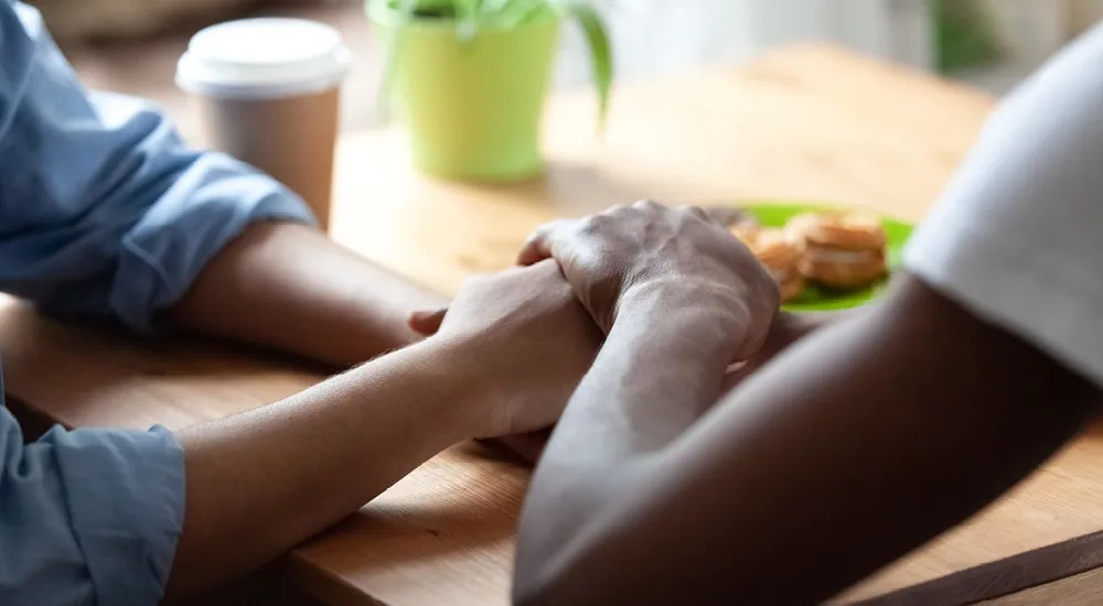 Two people grasping hands compassionately.