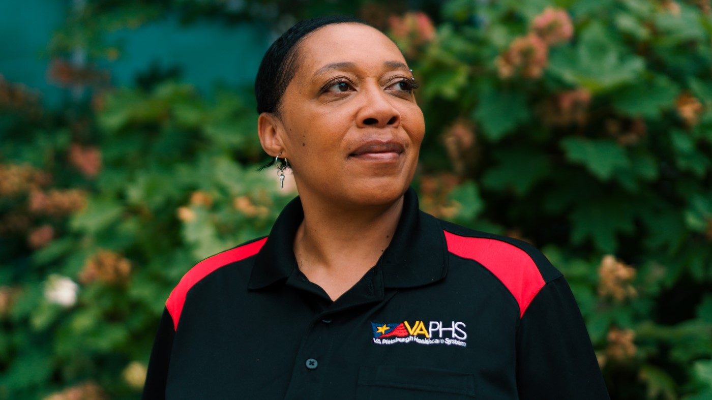 A VA primary care provider, standing outside and in front of trees.