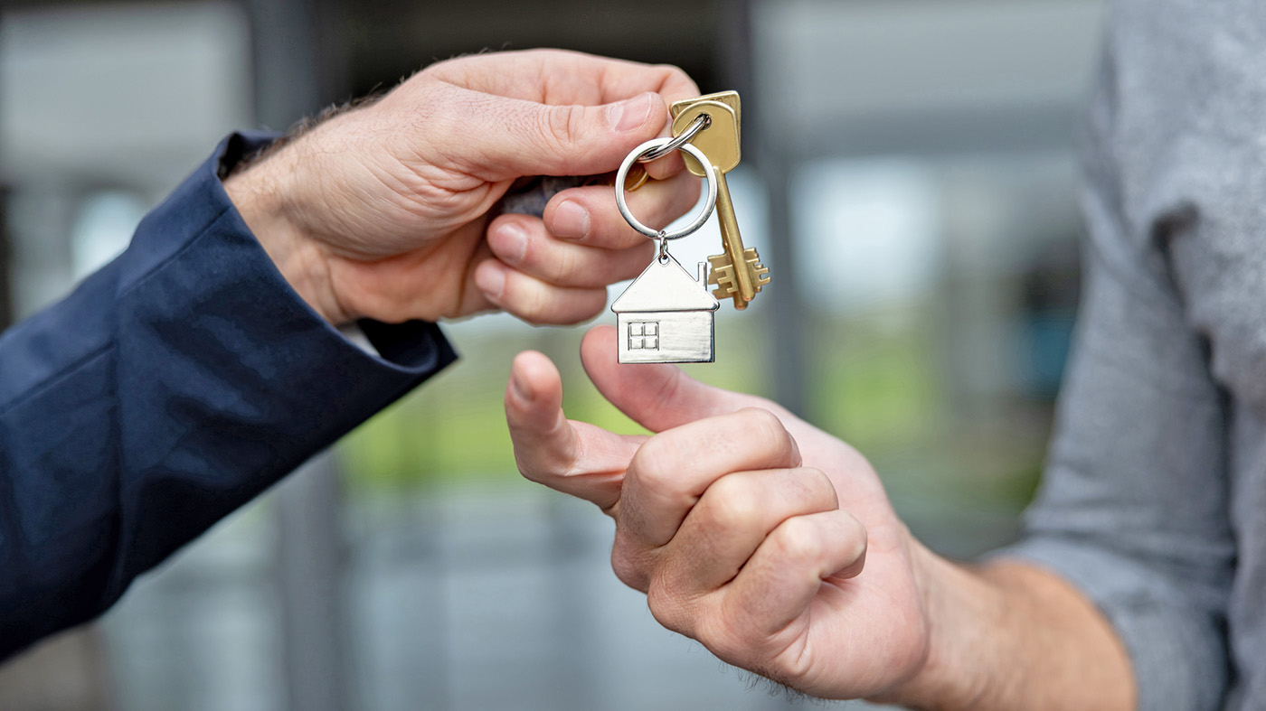 One hand giving another hand a set of keys on ring with a home; ending Veteran homelessness