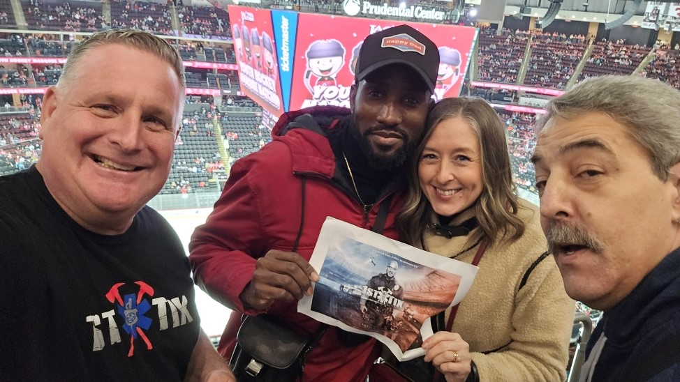 Group of people at a sporting event holding a sign thanking 1st Tix.